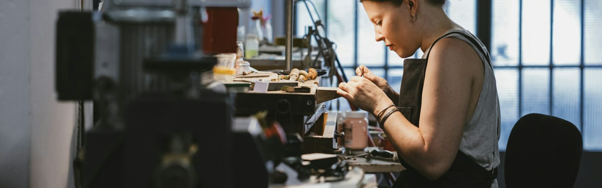 Female Jeweller At Work In Jewellery Workshop